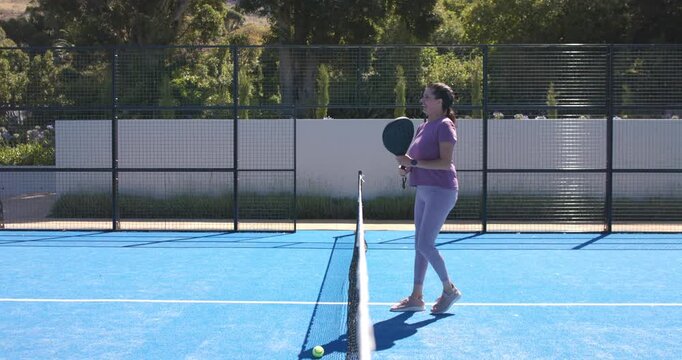 Diverse women on blue court, first tossing ball making second in visor tapping paddles, copy space