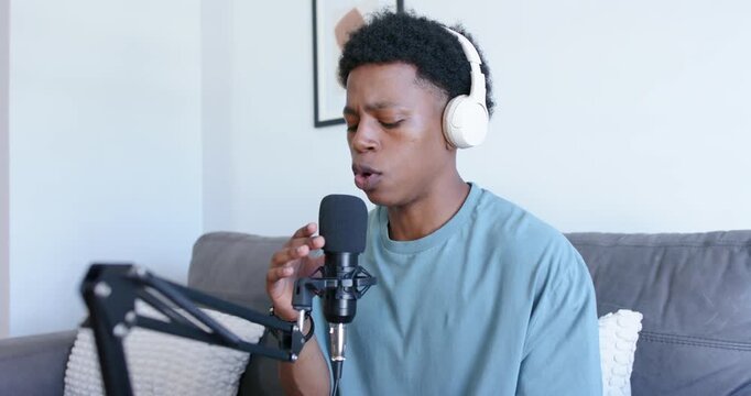 Male singer on couch starting music recording by adjusting mixer, singing into mic, waveform rising