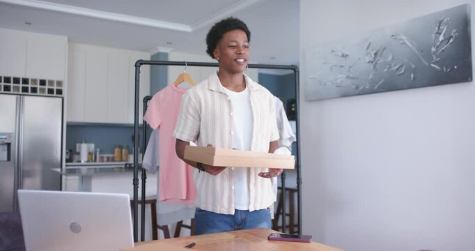 Small business owner standing at kitchen table, waving then opening shoebox showing item features