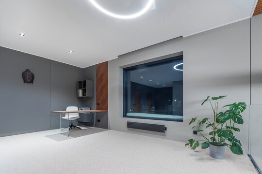 A spacious high-tech room decorated in white and gray. Panoramic window, modern furniture.