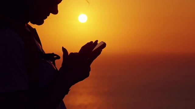 Close View Woman Using Smartphone While Standing at Cliff Edge During Golden Sunset with Ocean Background, Traveler Communicating Navigation Technology Travel Lifestyle
