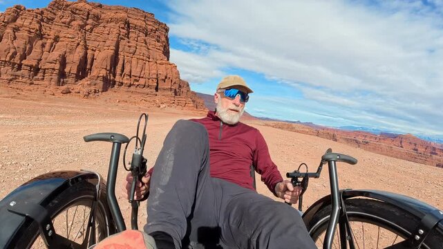 Senior cyclist is riding a full suspension recumbent tricycle off road at Thelma and Louise Point overlooking Colorado River canyon near Moab, Utah