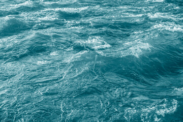 Fototapeta premium Water moving in a wild river with rocks in real time. Ocean fast motion, Sea storm with turquoise waves Aerial landscape, Ecology and clean water, Nature Concept.