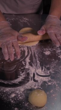 Kneading the pie dough. A woman rolls out the dough in the kitchen