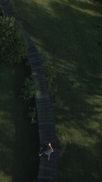 Aerial drone view of a man running on a grassy forest hills and mountains with a trail