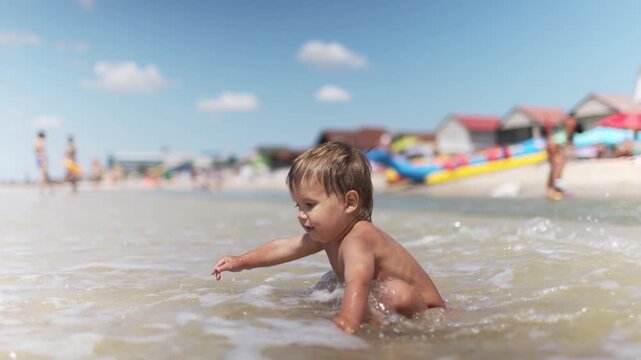 Kid collects shells and pebbles in the sea on a sandy bottom under the summer sun on a vacation