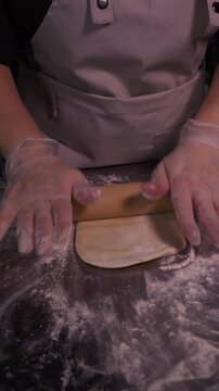 Kneading the pie dough. A woman rolls out the dough in the kitchen