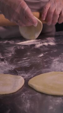 Kneading the pie dough. A woman rolls out the dough in the kitchen