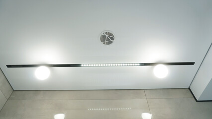 Modern minimalist ceiling with magnetic track lighting and circular ventilation grille.