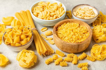 Assortment of uncooked Italian pasta in bowls on background. Variety of dry pasta, top view, food background. Different types of uncooked pasta. ingredients. flat lay. Assorted uncooked Italian pasta 