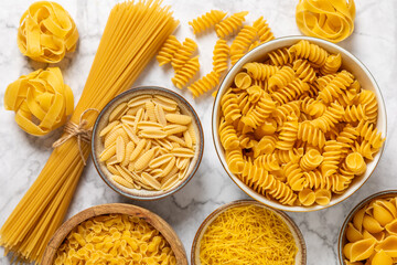 Assortment of uncooked Italian pasta in bowls on background. Variety of dry pasta, top view, food background. Different types of uncooked pasta. ingredients. flat lay. Assorted uncooked Italian pasta 