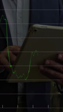 Vertical video: Man tapping pad peer viewing pad causing market charts and bars to rise for trading