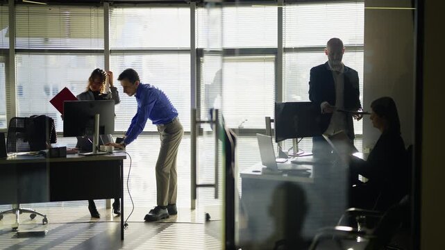 Business professionals engage in collaborative work within a contemporary office setting. Employees focus on tasks and utilize technology in a bright, modern workspace.