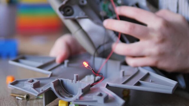 Child Hands Installing Glowing Red LED Light Into Plastic Scale Model Airplane Kit &mdash; STEM Hobby Electronics, Model Building with Wiring and Lighting Effect Close Up