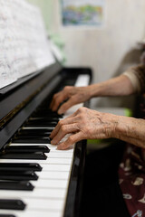Obraz premium an old person's hands playing piano, close-up of hands, in a home environment