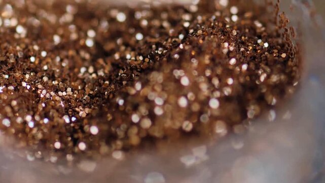 Macro Video of Bronze Metallic Glitter Particles Swirled with a Craft Tool
