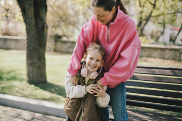 Happy mother and daughter relaxing in a park on sunny day.
