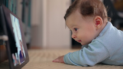 Baby watching tablet closely during video call, showing excitement and curiosity, digital...