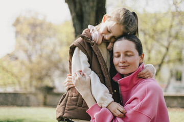 Happy mother and daughter relaxing in a park on sunny day.