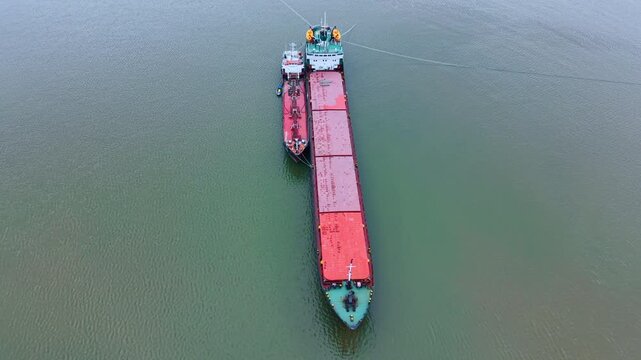 Two cargo ships moored together in open water aerial. Large bulk carrier vessel and smaller tanker ship connected for fuel or cargo transfer.