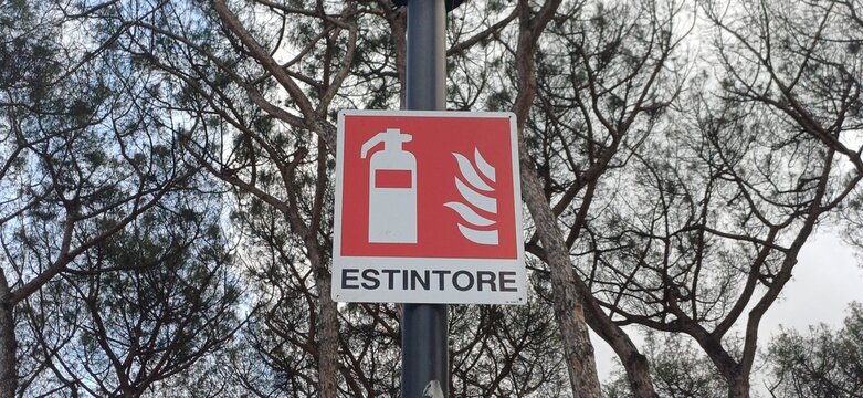 Italienisches Hinweisschild f&uuml;r Feuerl&ouml;scher Estintore vor Pinienb&auml;umen im Freien