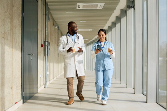Happy black doctor and nurse having a coffee break at medical clinic.