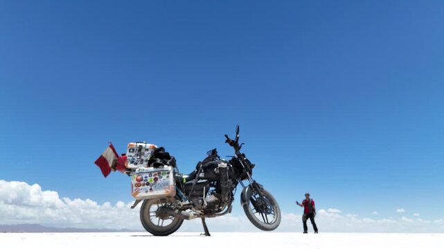 Man riding adventure motorcycle on Salar de Uyuni. Endless white landscape and rider on the vast Bolivian salt flats.