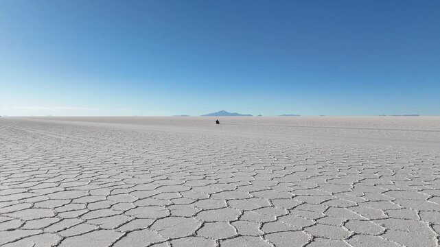 Man riding adventure motorcycle on Salar de Uyuni. Endless white landscape and rider on the vast Bolivian salt flats.