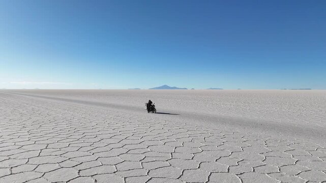 Man riding adventure motorcycle on Salar de Uyuni. Endless white landscape and rider on the vast Bolivian salt flats.