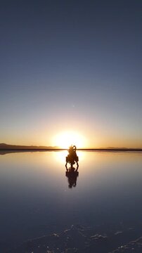 Man riding adventure motorcycle on Salar de Uyuni. Endless white landscape and rider on the vast Bolivian salt flats.
