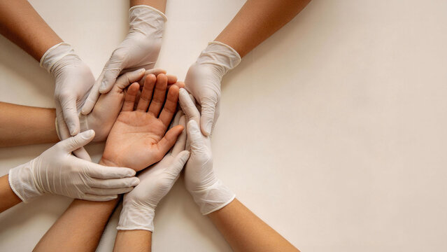 Healthcare workers wearing medical gloves gently  supporting a patient's hand in unity and care gesture, symbolizing compassion and medical support for International Red Cross and Red Crescent Day