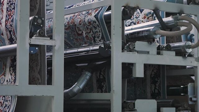 Automated industrial machinery processing a patterned carpet on a textile factory production line