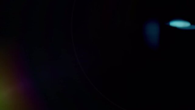 Abstract light leak with rainbow spectrum and bright flare on black background.