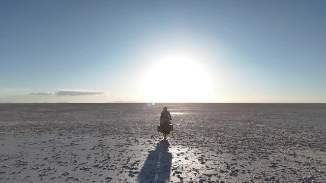 Man riding adventure motorcycle on Salar de Uyuni. Endless white landscape and rider on the vast Bolivian salt flats.
