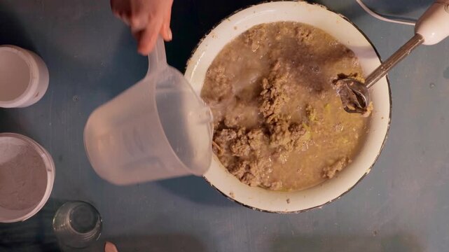 Step 2 of papier mache making process. Hands soaking torn egg carton pieces in water to soften recycled paper for craft pulp mixture. DIY recycled paper craft preparation