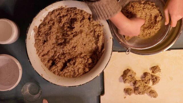 Step 3 of papier mache process. Hands squeezing soaked recycled paper pulp to remove water and prepare material for handmade craft mixture