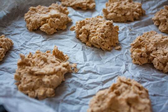 Baking tray with uncooked raw oatmeal cookie dough on a white baking paper