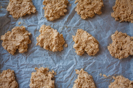 Baking tray with uncooked raw oatmeal cookie dough on a white baking paper