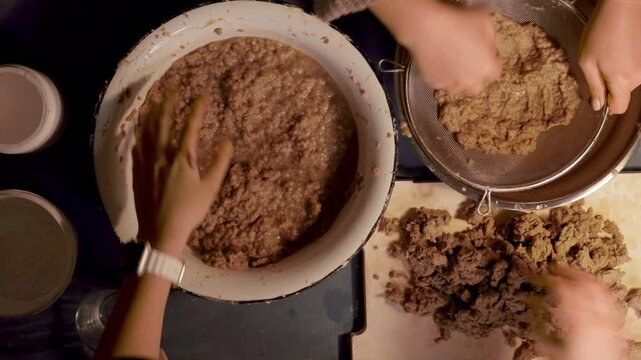 Step 2 of papier mache making process. Hands soaking torn egg carton pieces in water to soften recycled paper for craft pulp mixture. DIY recycled paper craft preparation