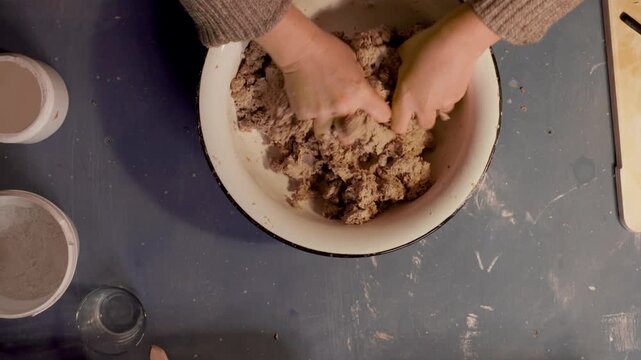 Step 4 of papier mache making process. Hands adding glue to prepared recycled paper pulp to create craft mixture for handmade papier mache projects