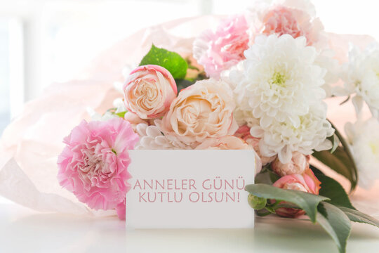  bouquet of pink carnations white chrysanthemums peach roses with greeting card text anneler g n kutlu olsun - happy mothers day in turkish,  floral composition for mother day celebration greeting 