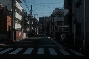 Obraz premium Quiet residential street with crosswalk and overhead power lines in urban Japan