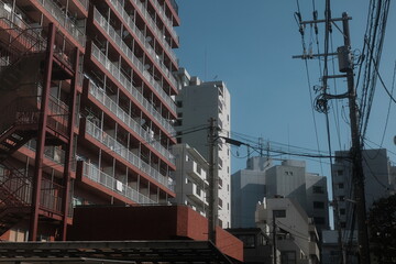 Fototapeta premium Urban apartment buildings with power lines and blue sky in a Japanese city neighborhood