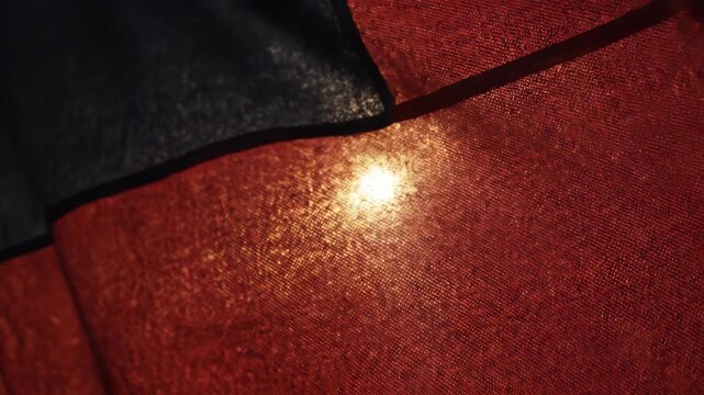 Extreme macro of deep red flag fabric in motion, backlit by the low morning sun, revealing glowing threads and the intricate, wind-blown weave.