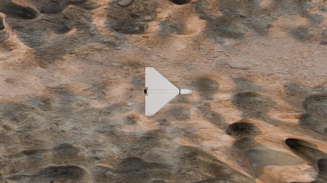 3D animation of a kamikaze drone that flies from left to right over a canyon. The camera looks down on the drone from above. 