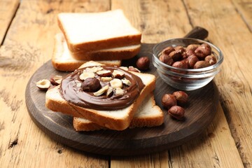 Fototapeta premium Toasts with chocolate paste and hazelnuts on wooden table, closeup