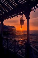 Fototapeta premium Golden sunset light paints the Pacific Ocean as waves roll beneath the iconic La Rosa Nautica restaurant on the Miraflores coast in Lima, Peru. The tranquil seaside atmosphere evokes an active coastal