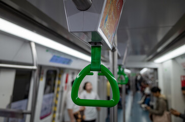 Green hand strap on subway with commuters © MarshallChan