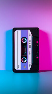 Retro audio cassette tape on vibrant colorful gradient background representing vintage music technology.