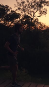 Silhouette of man running on grassy hill at golden hour sunset sunrise